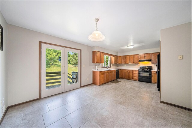 kitchen featuring light countertops, under cabinet range hood, a sink, black appliances, and brown cabinetry