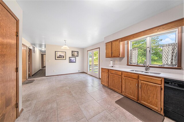 kitchen with light countertops, dishwasher, brown cabinets, a sink, and light tile patterned floors