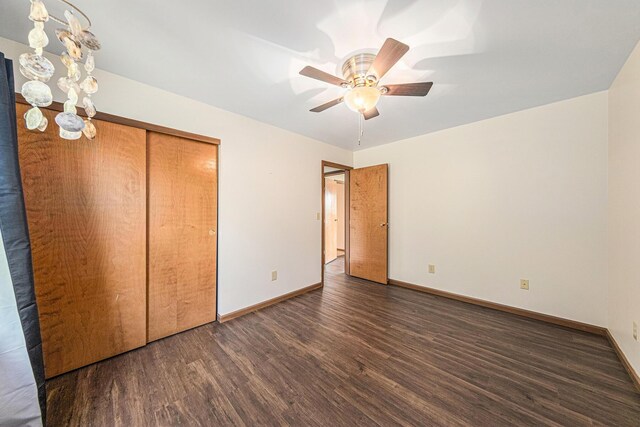 unfurnished bedroom featuring baseboards, a closet, wood finished floors, and ceiling fan