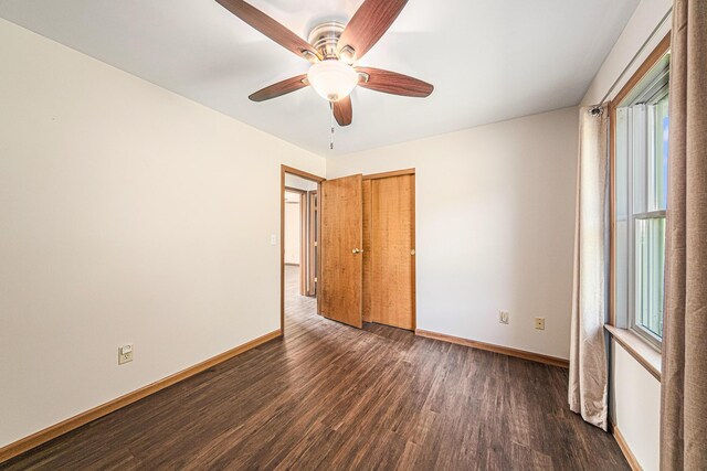 unfurnished bedroom featuring baseboards, a closet, wood finished floors, and ceiling fan