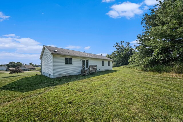 back of property with entry steps and a yard