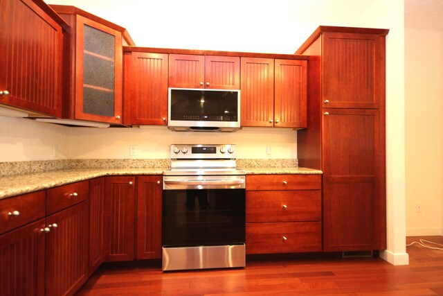 14224 Bridgeview Pointe, Vicksburg, MI 49097 - kitchen featuring appliances with stainless steel finishes, dark wood-style flooring, glass insert cabinets, light stone countertops, and baseboards