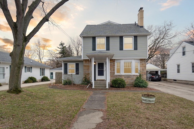 view of front of property featuring stone siding, a chimney, a front lawn, and driveway