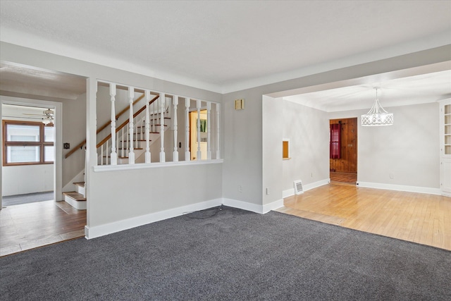 empty room featuring stairs, wood finished floors, baseboards, and carpet flooring