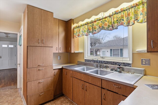 kitchen featuring light countertops, brown cabinetry, a sink, and light tile patterned floors