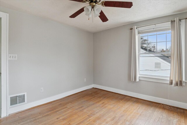 unfurnished room featuring wood-type flooring, baseboards, a textured ceiling, visible vents, and a ceiling fan