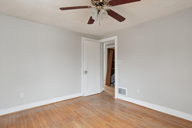 empty room with a textured ceiling, baseboards, visible vents, light wood-style floors, and ceiling fan