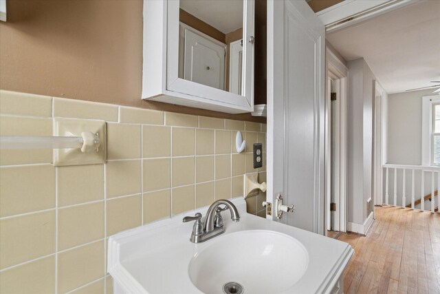 bathroom featuring tile walls, a sink, and hardwood / wood-style floors