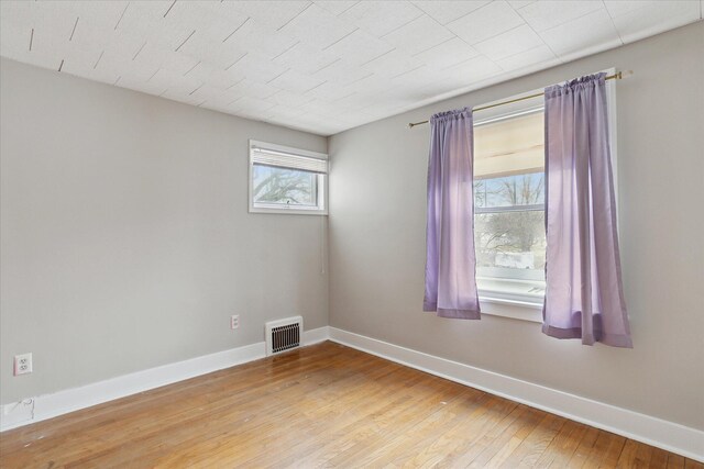 empty room with light wood finished floors, baseboards, and visible vents