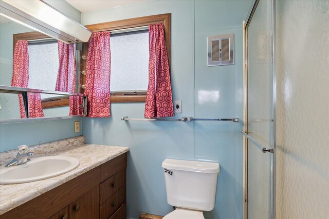 bathroom featuring a shower with door, visible vents, toilet, and vanity