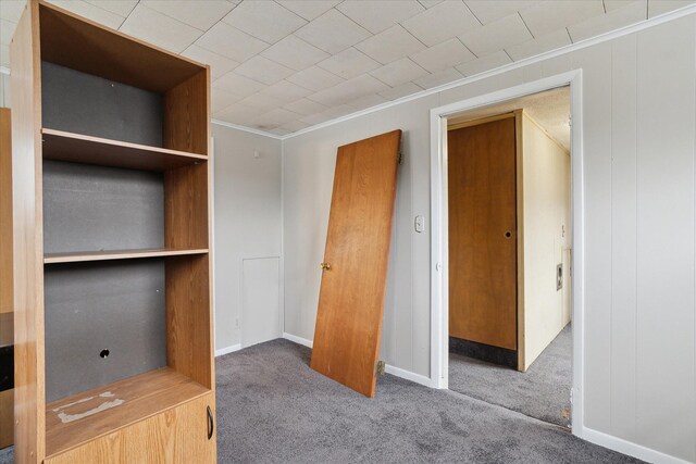 unfurnished bedroom featuring baseboards, carpet floors, and crown molding