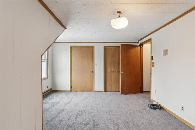 unfurnished bedroom featuring two closets, carpet, baseboards, and crown molding
