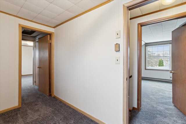 corridor featuring baseboards, crown molding, a baseboard heating unit, and carpet flooring