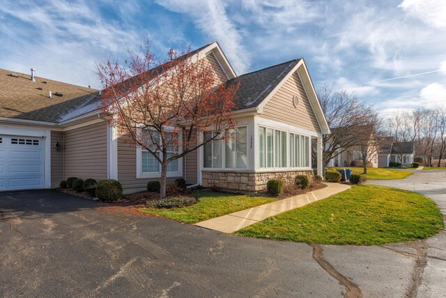 1998 Brighton Ln, Portage, MI 49024 - view of side of property with a lawn, stone siding, an attached garage, and aphalt driveway