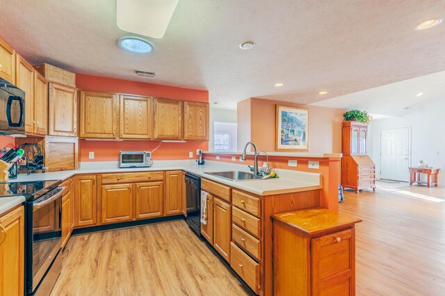 1998 Brighton Ln, Portage, MI 49024 - kitchen with light countertops, a sink, light wood-style flooring, a peninsula, and black appliances