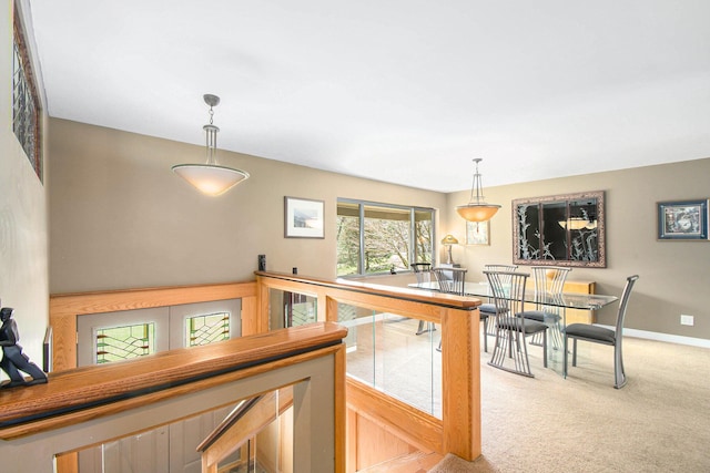 kitchen featuring hanging light fixtures, baseboards, and light colored carpet