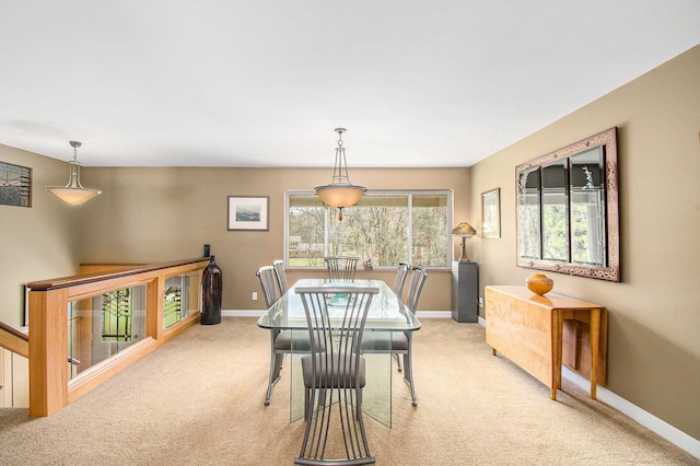 dining space featuring baseboards and light carpet