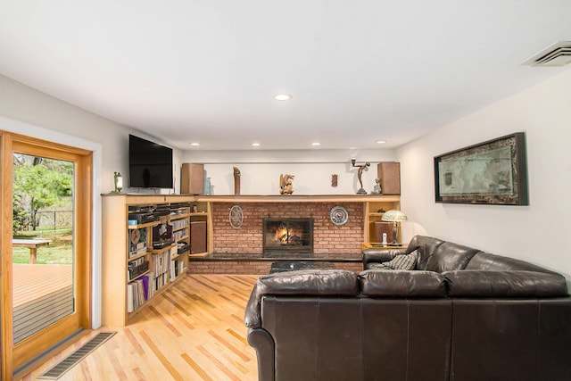 living area featuring light wood-style flooring, a brick fireplace, visible vents, and recessed lighting