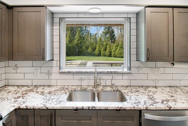 kitchen featuring tasteful backsplash, light stone counters, dark brown cabinets, dishwasher, and a sink