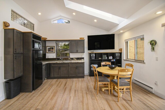 dining room with light wood-style flooring, vaulted ceiling with skylight, a baseboard radiator, and recessed lighting