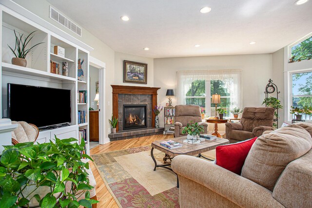 5091 E High Tower Lake Rd, Hesperia, MI 49421 - living room with light wood finished floors, a wealth of natural light, visible vents, and a tile fireplace