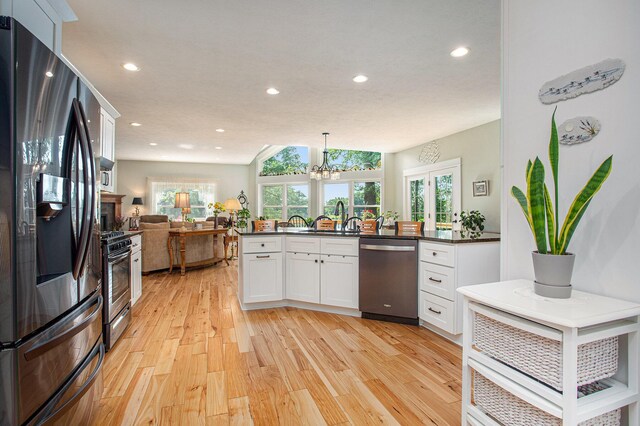 5091 E High Tower Lake Rd, Hesperia, MI 49421 - kitchen featuring open floor plan, dark countertops, light wood-style floors, white cabinets, and appliances with stainless steel finishes