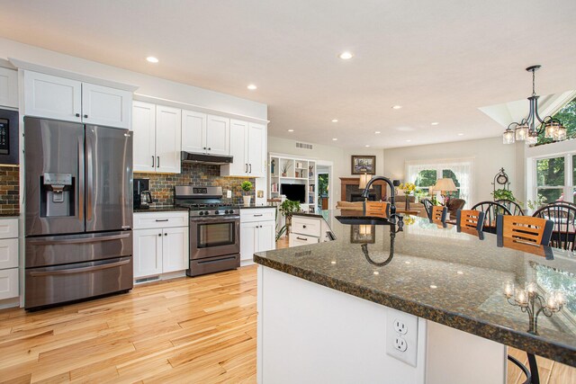 5091 E High Tower Lake Rd, Hesperia, MI 49421 - kitchen featuring appliances with stainless steel finishes, under cabinet range hood, a sink, a kitchen breakfast bar, and a notable chandelier