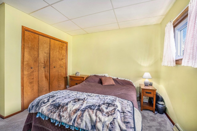 carpeted bedroom featuring baseboards, baseboard heating, a closet, and a paneled ceiling