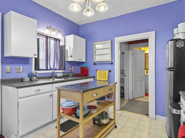 817 E Loomis St, Ludington, MI 49431 - kitchen featuring white cabinets, a chandelier, light floors, a sink, and freestanding refrigerator