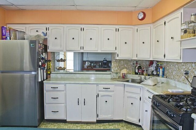 25544 Gage St, Dowagiac, MI 49047 - kitchen with freestanding refrigerator, black range with gas stovetop, a paneled ceiling, a sink, and white cabinets