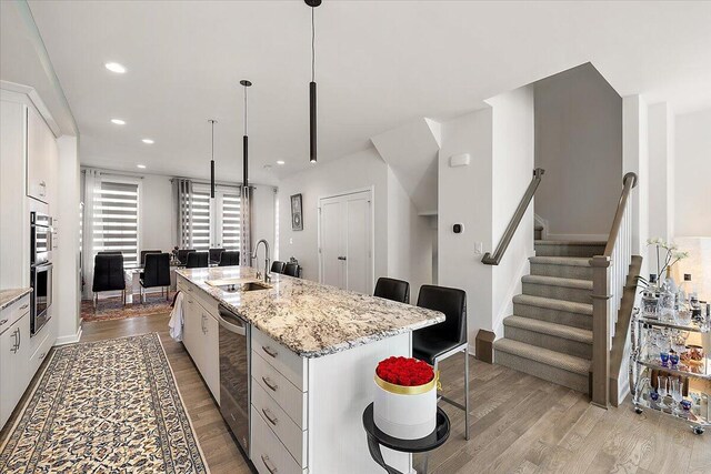2824 Ridington Rd, Ann Arbor, MI 48105 - kitchen featuring light wood-type flooring, a sink, a breakfast bar area, and a kitchen island with sink