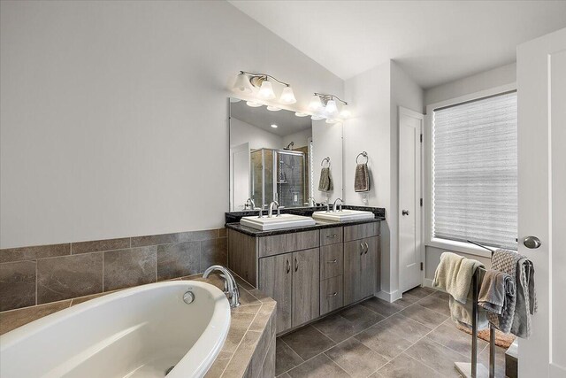 2824 Ridington Rd, Ann Arbor, MI 48105 - full bathroom with double vanity, a bath, a shower stall, vaulted ceiling, and a sink