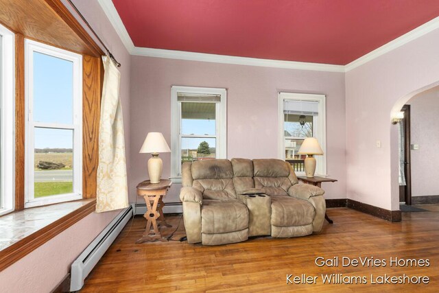 living room featuring arched walkways, crown molding, wood finished floors, and baseboard heating