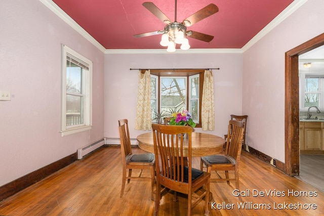 dining area featuring baseboards, wood finished floors, ornamental molding, and a ceiling fan