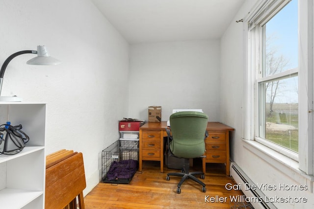 office area featuring a baseboard radiator, wood finished floors, and a healthy amount of sunlight