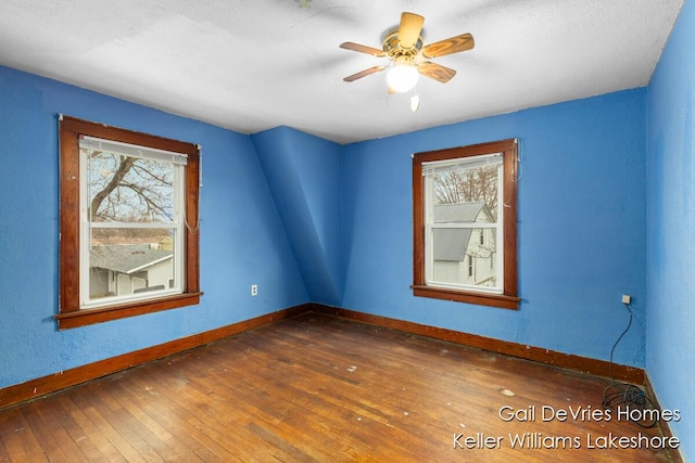 unfurnished room featuring wood-type flooring, a ceiling fan, and baseboards