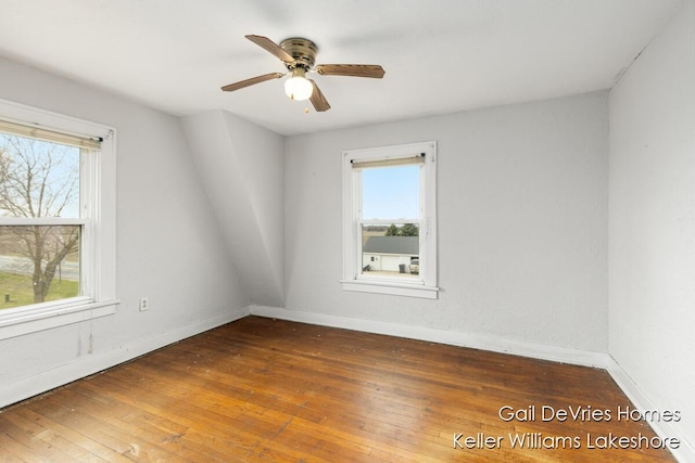 spare room with wood-type flooring, a ceiling fan, and baseboards