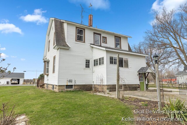 rear view of property with a gambrel roof, roof with shingles, a yard, and a chimney