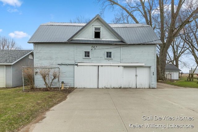 rear view of house featuring a lawn and metal roof