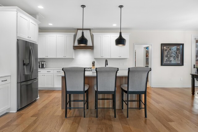8114 Turning Stone, Kalamazoo, MI 49009 - kitchen featuring a kitchen bar, custom exhaust hood, stainless steel fridge, and light wood-style floors