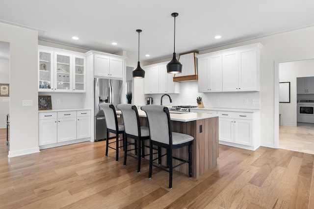 8114 Turning Stone, Kalamazoo, MI 49009 - kitchen with light countertops, stainless steel fridge with ice dispenser, a kitchen breakfast bar, light wood-type flooring, and stove