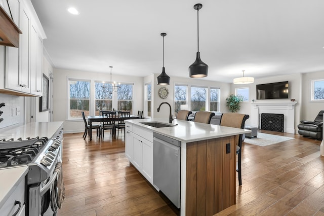 8114 Turning Stone, Kalamazoo, MI 49009 - kitchen featuring dark wood-style flooring, a fireplace, a kitchen bar, appliances with stainless steel finishes, and a sink