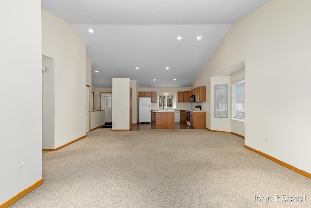 7588 Rivendell Dr SE, Grand Rapids, MI 49508 - unfurnished living room with high vaulted ceiling, baseboards, light colored carpet, and recessed lighting