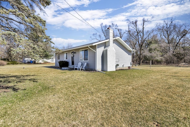 back of house featuring a lawn and a chimney