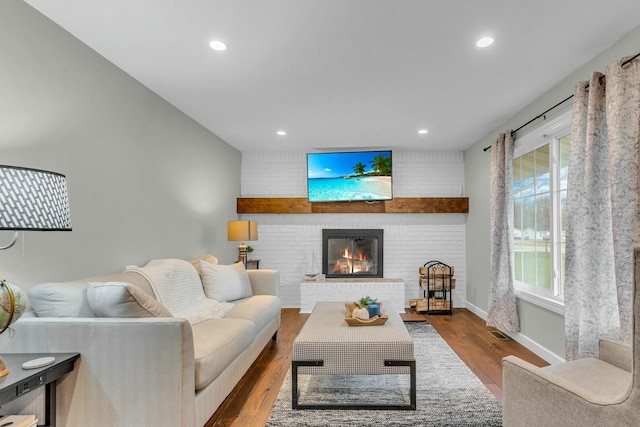 living area featuring visible vents, baseboards, a fireplace, wood finished floors, and recessed lighting