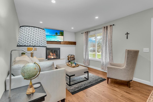 living area featuring baseboards, a fireplace, wood finished floors, and recessed lighting