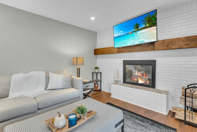 living room with a fireplace, recessed lighting, wood finished floors, and brick wall