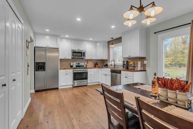 kitchen with white cabinetry, stainless steel appliances, tasteful backsplash, and light wood finished floors