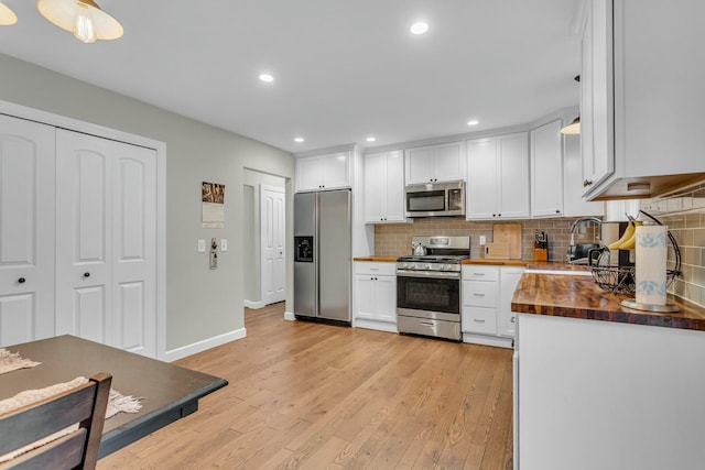 kitchen with white cabinetry, tasteful backsplash, butcher block countertops, appliances with stainless steel finishes, and light wood-style flooring