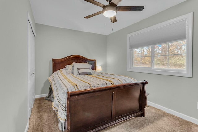 carpeted bedroom featuring a ceiling fan, a closet, and baseboards